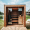 Aera European Outdoor Sauna in front of water and grass.