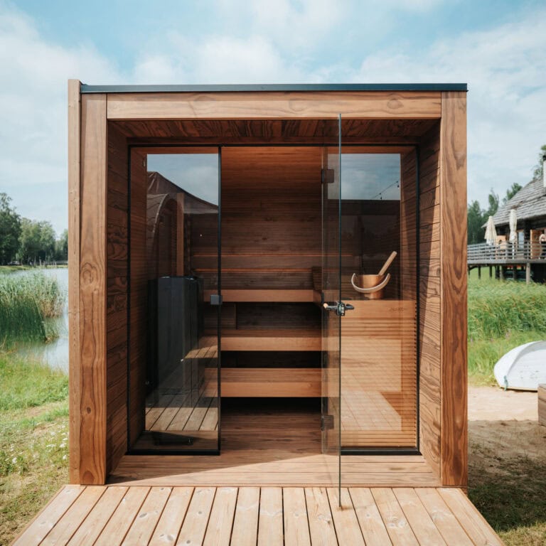 Aera European Outdoor Sauna in front of water and grass.