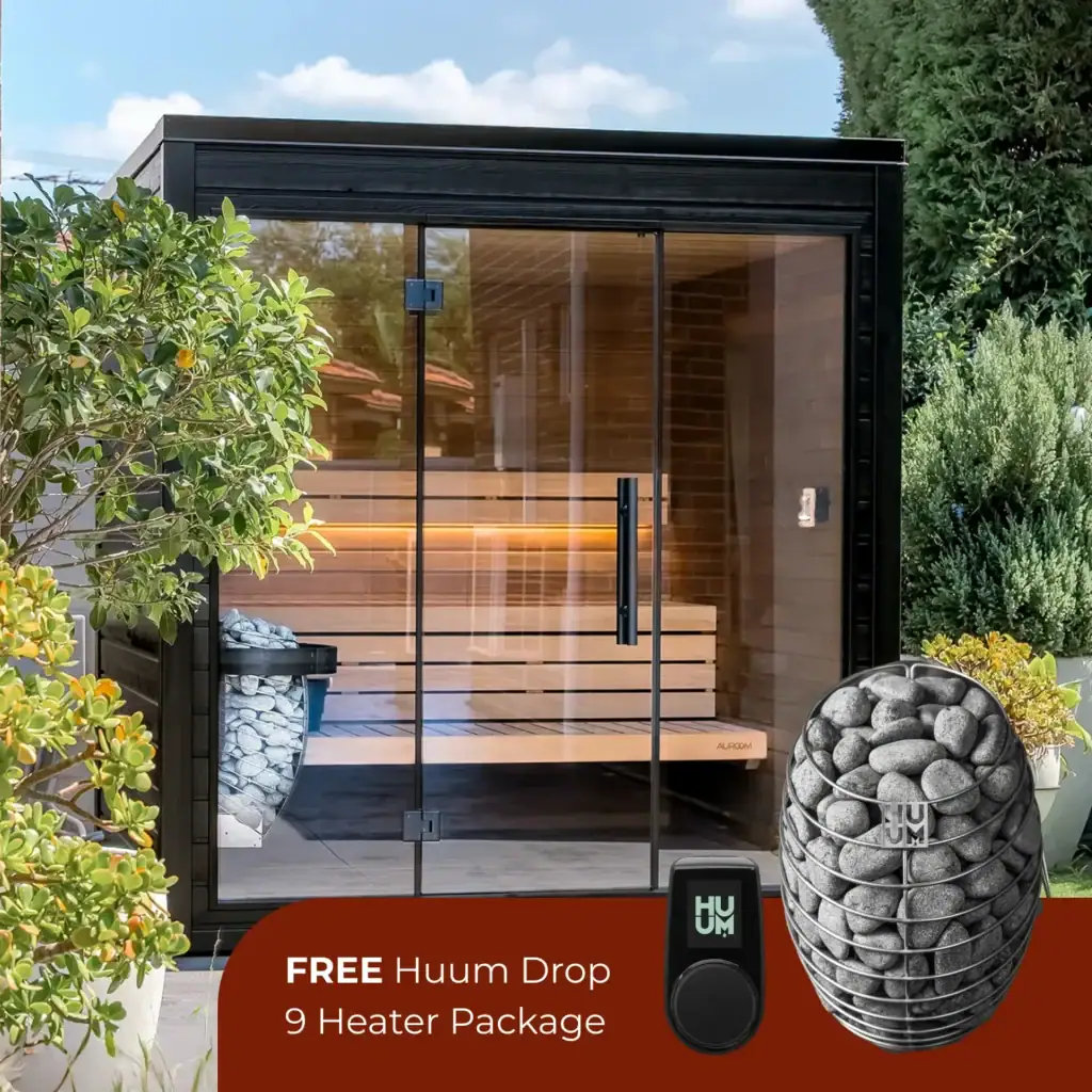Outdoor glass-walled sauna with wooden benches visible inside, surrounded by greenery; bottom banner advertises a free Huum Drop 9 Heater Package.
