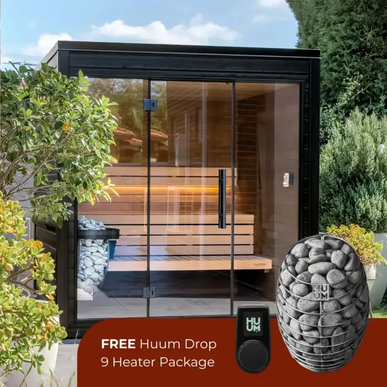 Outdoor glass-walled sauna with wooden benches visible inside, surrounded by greenery; bottom banner advertises a free Huum Drop 9 Heater Package.