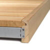 Close-up of a wooden step with a gray metal bracket and screws, viewed from the side.