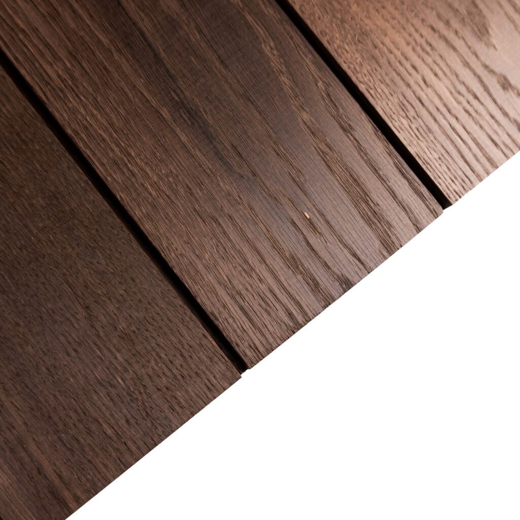 Close-up of brown wood floor planks with visible grain running along the boards and a white curved background edge at the bottom-right.